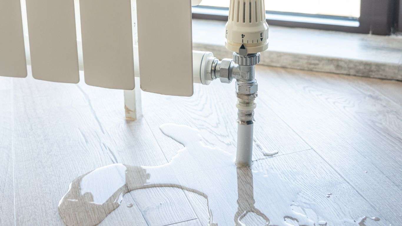 Radiator pipe leaking onto hardwood floor which signifies the need for water leak detection